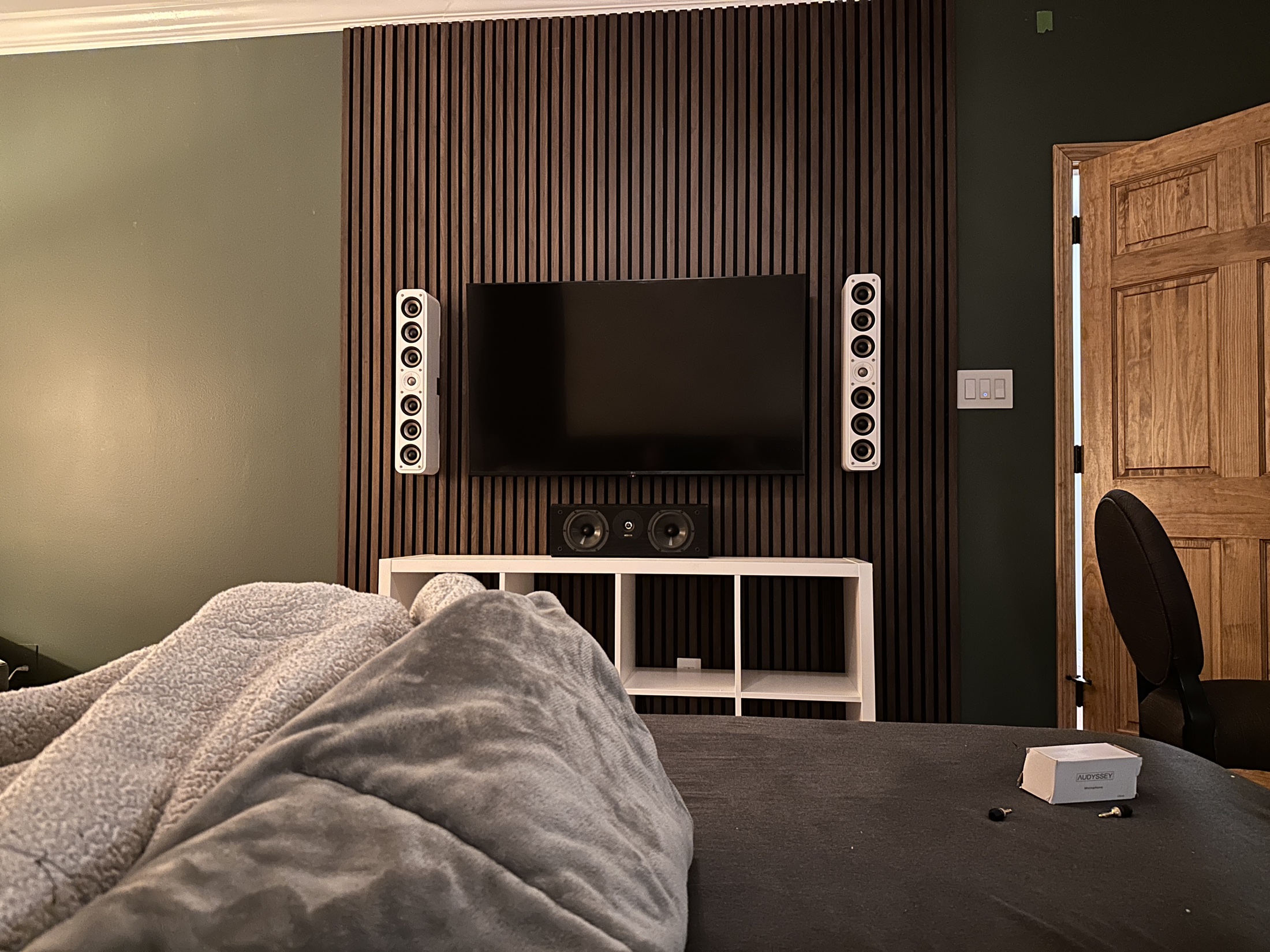 Recent St. Louis TV installation with a wall-mounted screen, concealed wiring, acoustic wood slat wall, and mounted speakers
