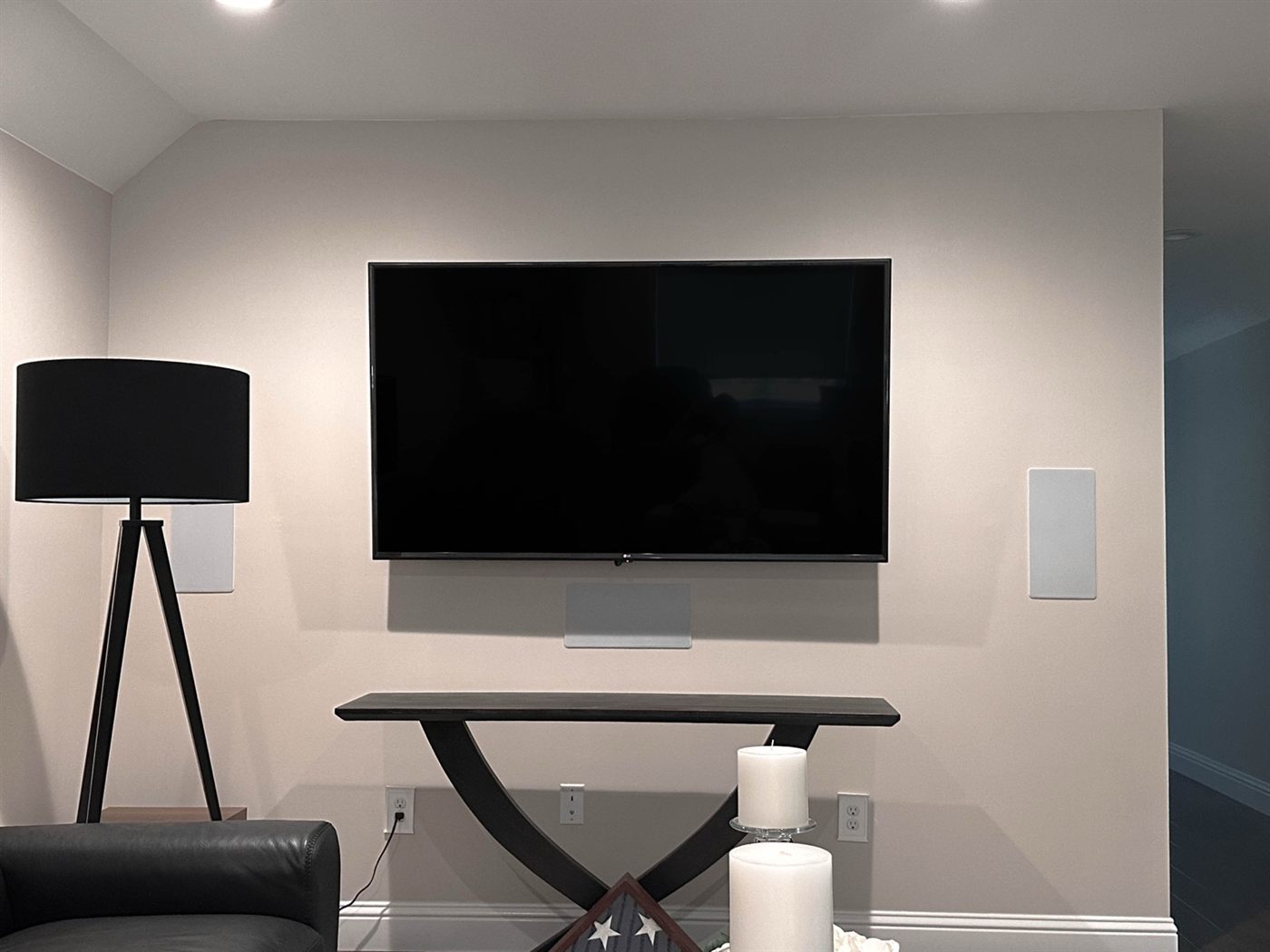 Family room TV set at seated eye level above a console, with a soundbar and in-wall speaker flanking the screen