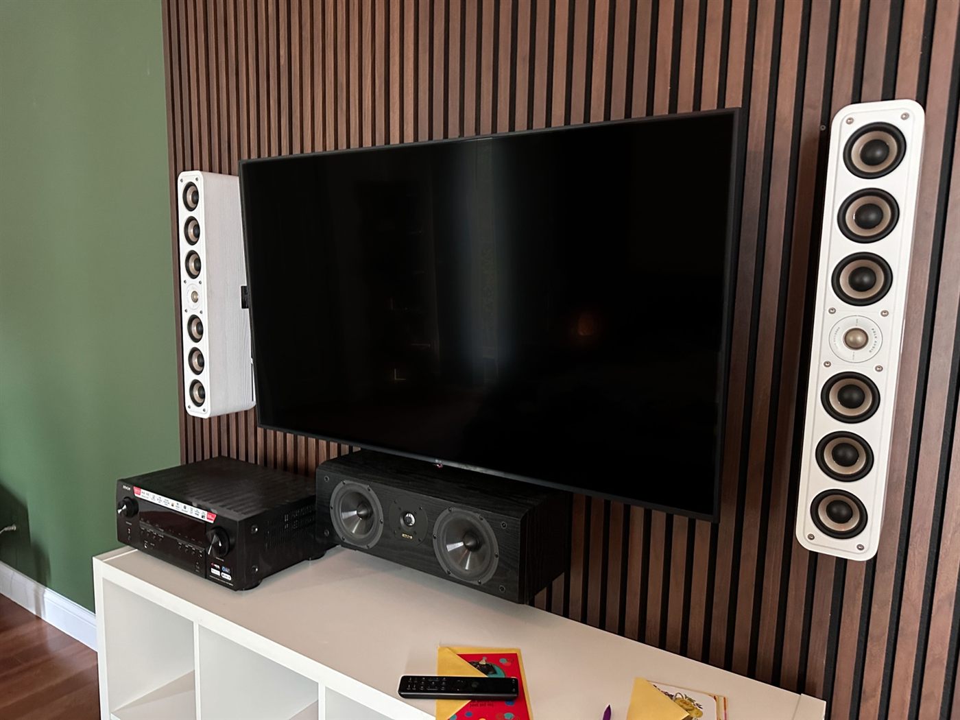 Town and Country media wall finished in walnut slats with a mounted TV, tower speakers, and receiver