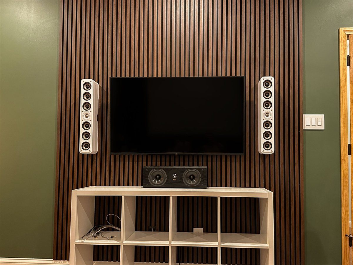 Walnut slat media wall with a mounted TV, on-wall speakers either side, and a center channel on the console