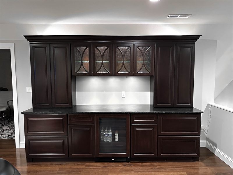 Wide view of the same built-in run with the glass uppers lit and the backsplash washed with LED light