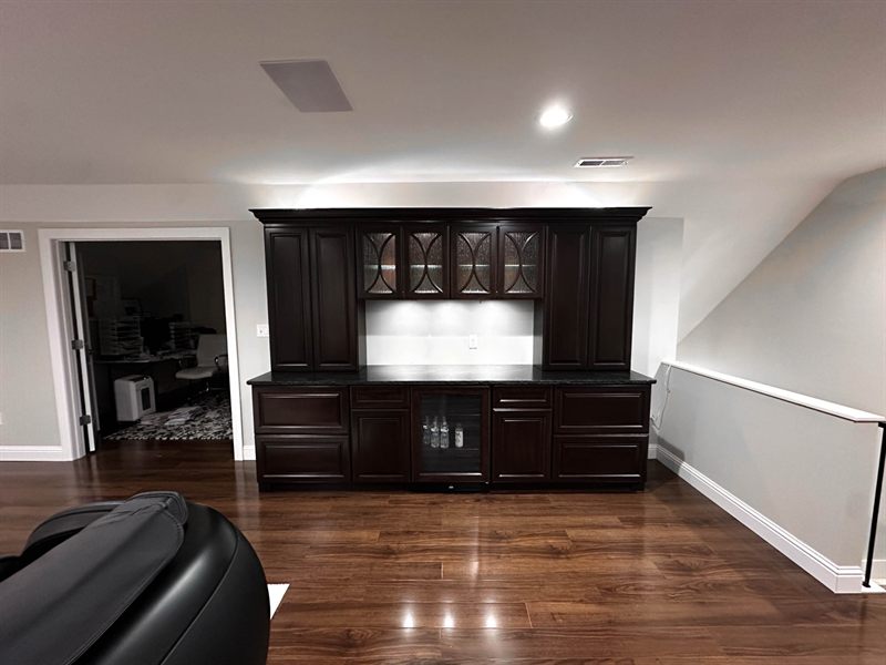 The lit cabinetry seen from across the room, showing how the lighting reads against the dark joinery