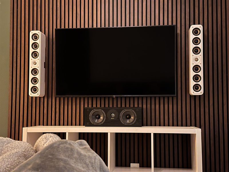 Walnut slat wall with a centered TV, in-wall speakers, and a center channel below